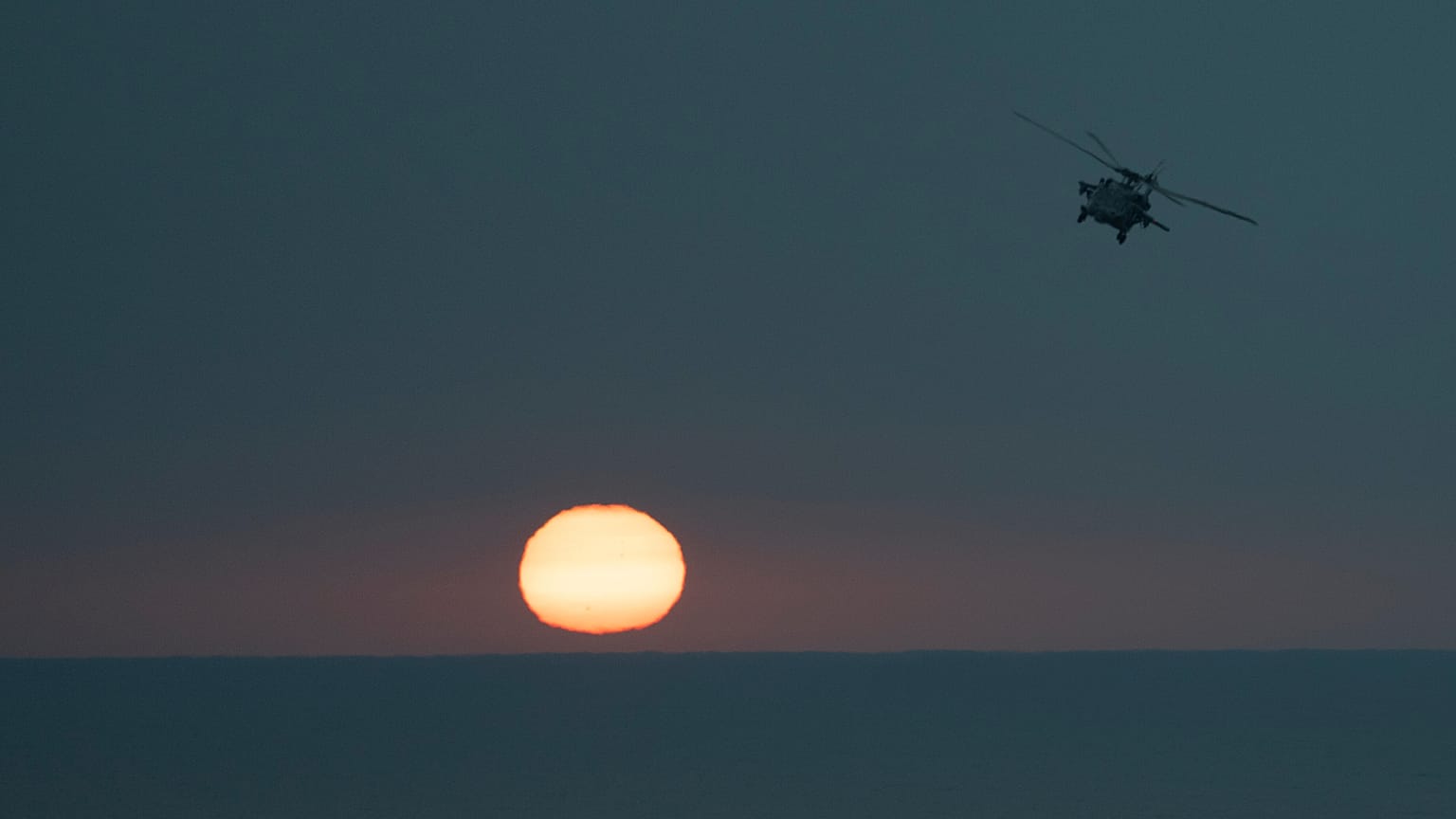 An MH-60S Seahawk helicopter flies back to the U.S.S. aircraft carrier Dwight D. Eisenhower, also known as the 'IKE', in the south Red Sea