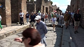 Visitors walk down an ancient Roman street in the Pompeii archeological site