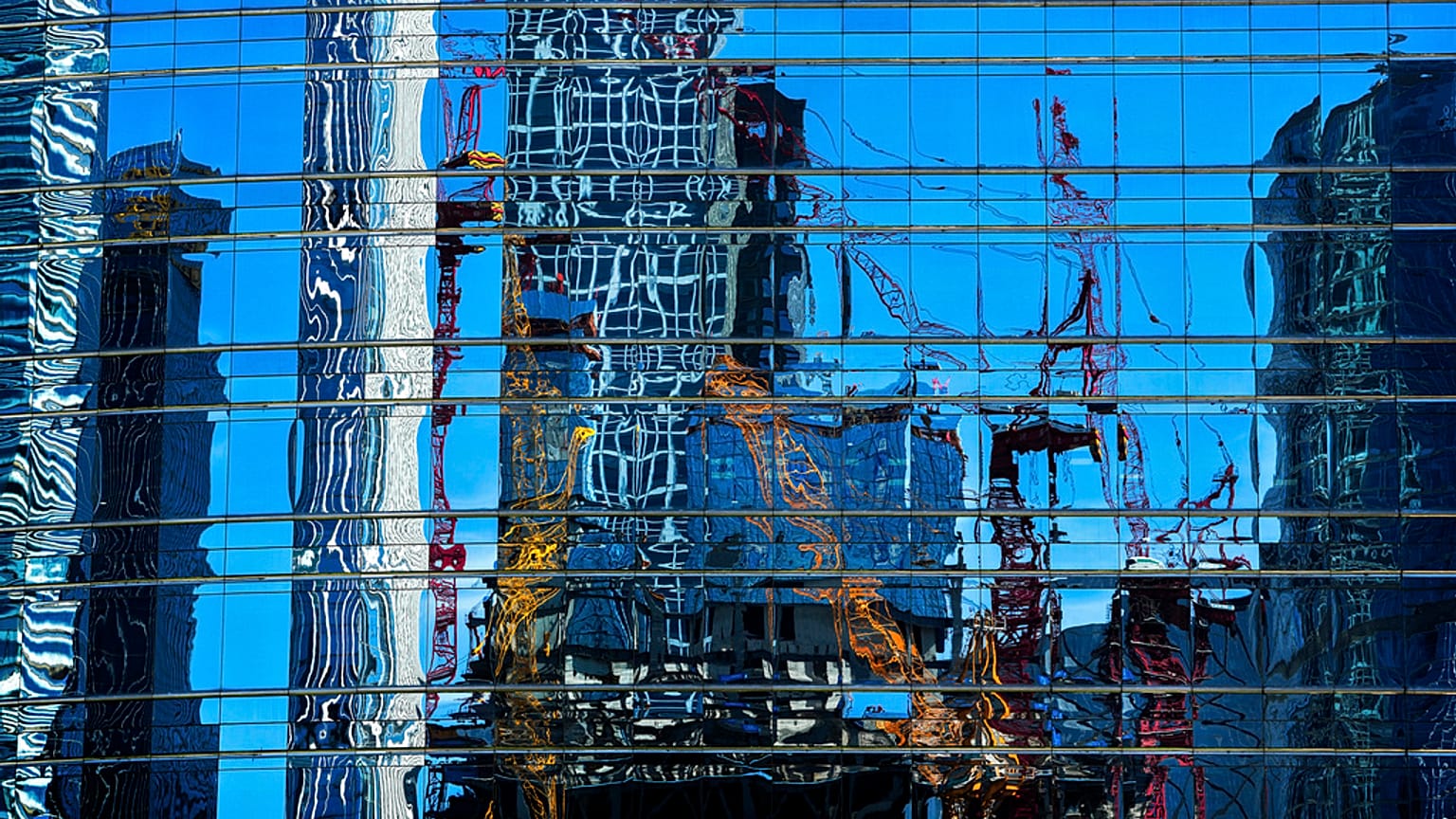Cranes at a construction site in the Central Business District are reflected on a window panels of an office building in Beijing, Sunday, May 26, 2024. 