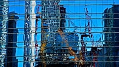 Cranes at a construction site in the Central Business District are reflected on a window panels of an office building in Beijing, Sunday, May 26, 2024. 