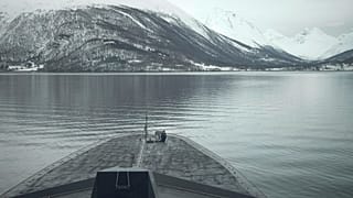 A French sailor sits at the bow of the French navy frigate Normandie during a patrol in a Norwegian fjord, north of the Arctic circle, Friday March 8, 2024.