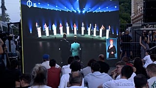 Παρακολούθηση του ντιμπέιτ σε έναν προβολέα μπροστά από το παζάρι του Castle Garden