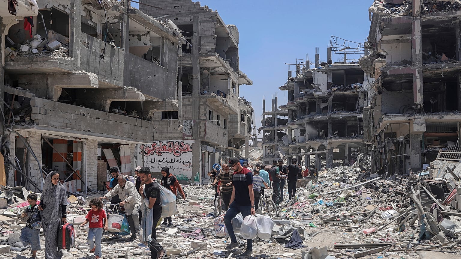 فلسطينيون يسيرون وسط الدمار الذي خلفه القصف الإسرائيلي على جباليا. 2024/05/30