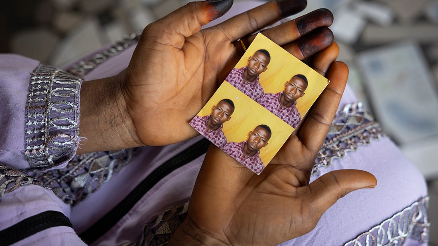 Η Mariama Sylla, αδελφή του Ousmane Sylla, κρατά φωτογραφίες του στο σπίτι τους στο Matoto Bonagui, προάστιο του Conakry, Γουινέα, Δευτέρα 8 Απριλίου 2024.