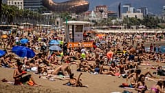As pessoas apanham banhos de sol na praia em Barcelona, Espanha.