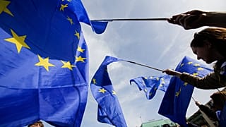 Un hombre viste un traje con los colores de la UE mientras camina frente al Parlamento Europeo