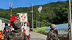 Globos con basura, presumiblemente enviados por Corea del Norte, cuelgan de cables eléctricos mientras soldados montan guardia en Muju, Corea del Sur.