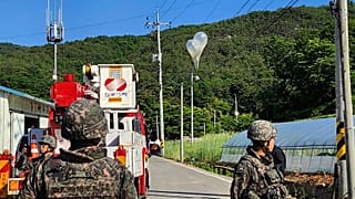 Balloons with trash presumably sent by North Korea, hang on electric wires as soldiers stand guard in Muju, South Korea.