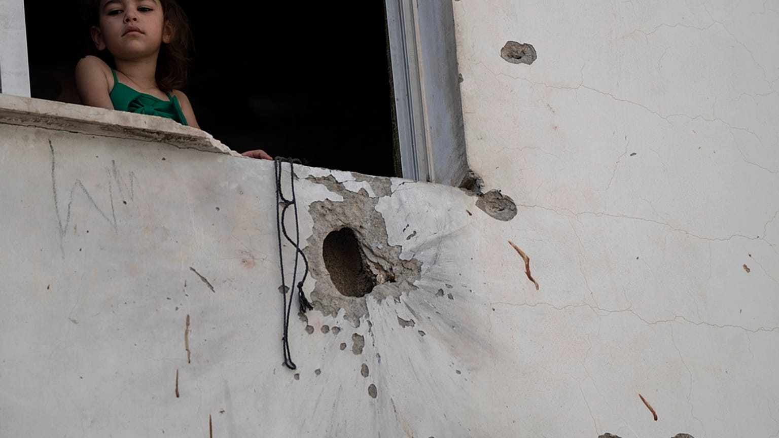 A girl looks out from a window of a building damaged by shrapnels after an Israeli forces raid in the West Bank Jenin refugee camp, Thursday, May 23, 2024. T