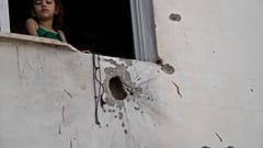 A girl looks out from a window of a building damaged by shrapnels after an Israeli forces raid in the West Bank Jenin refugee camp, Thursday, May 23, 2024. T