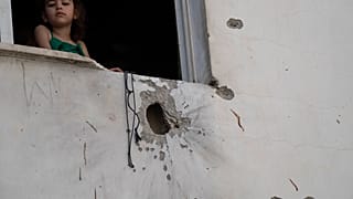 A girl looks out from a window of a building damaged by shrapnels after an Israeli forces raid in the West Bank Jenin refugee camp, Thursday, May 23, 2024. T