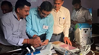 Polling officials check and seal an electronic voting machine before they allow voters to cast their votes at a polling station, India, Saturday, June 1, 2024.
