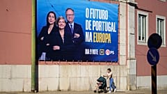 Una mujer empuja y su bebé pasan junto a una valla publicitaria del Partido Socialista para las elecciones europeas, en Lisboa, el viernes 31 de mayo de 2024.