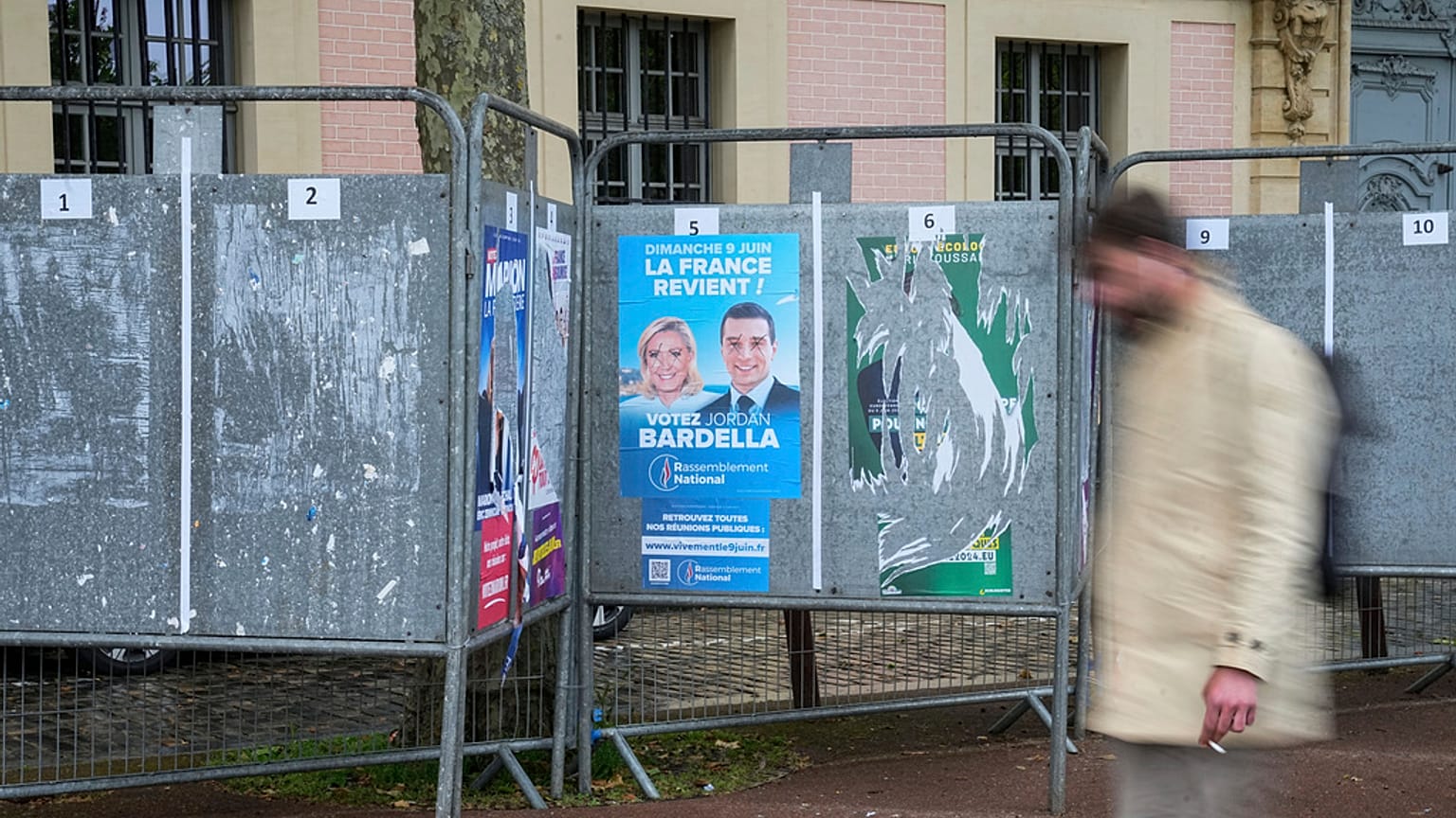 A man walks past a row of campaign boards for the upcoming European election in Versailles west of Paris, Friday, May 31, 2024. 