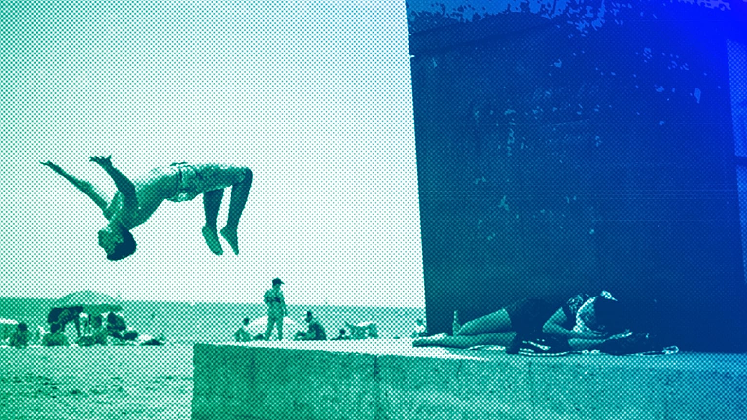 A boy does a back flip at Barcelona's beach, July 2021