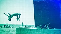 A boy does a back flip at Barcelona's beach, July 2021