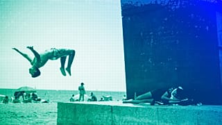 A boy does a back flip at Barcelona's beach, July 2021