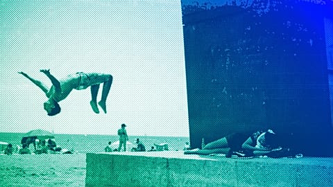 A boy does a back flip at Barcelona's beach, July 2021