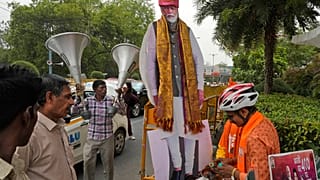 Apoiante do Bharatiya Janata Party oferece orações ao primeiro-ministro indiano Narendra Modi em frente à sede do partido em Nova Deli, Índia