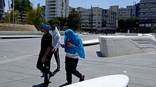 Περαστικοί προσπαθούν να προστατευτούν από τον καύσωνα στην πλατεία Ελευθερίας στην Λευκωσία