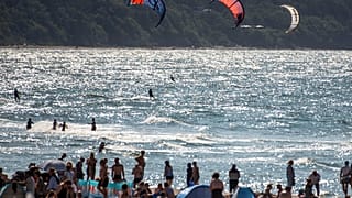 Parasörfçüler ve yüzücüler, 10 Haziran 2023 Cumartesi günü Almanya'nın Warnemuende kentinin Baltık Denizi sahilinde güneşin tadını çıkarıyor. 