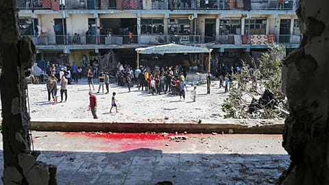 Palestinians look at the aftermath of the Israeli strike on a U.N.-run school that killed over 30