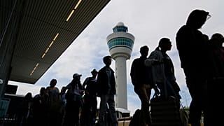 Viajeros hacen cola frente a la terminal para facturar y embarcar en los vuelos del aeropuerto Schiphol de Ámsterdam.