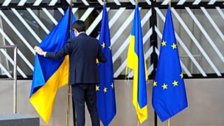 A member of protocol arranges the Ukrainian and EU flags during an EU summit at the European Council building in Brussels on Thursday, Feb. 9, 2023. 