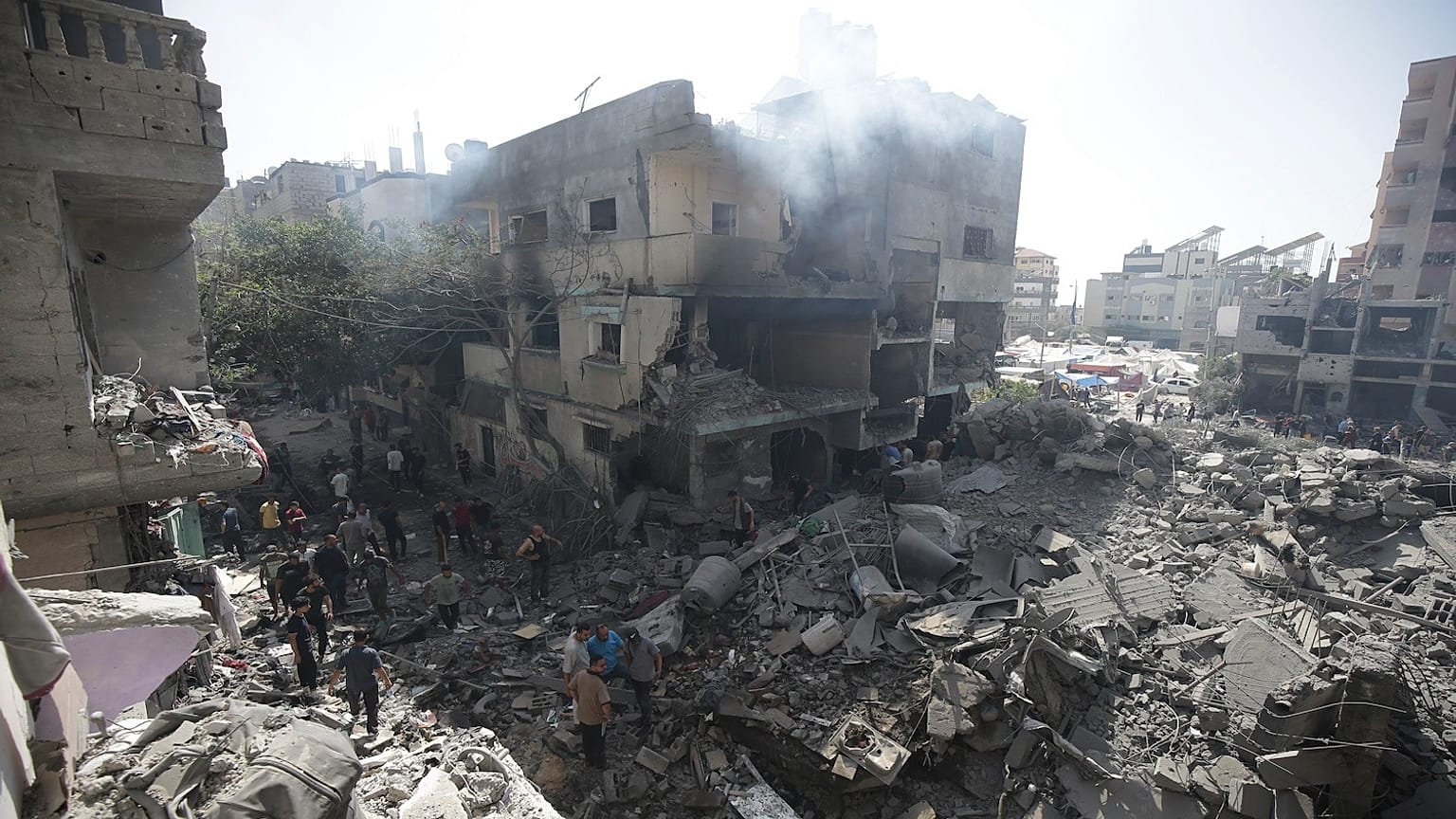 فلسطينيون ينظرون إلى آثار القصف الإسرائيلي على مخيم النصيرات بقطاع غزة، السبت 8 يونيو 2024.
