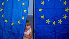 A child peers from a voting cabin during European and local elections in Baleni, 9 June 2024