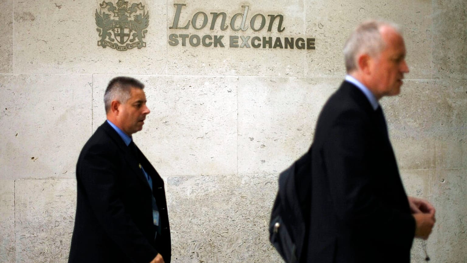 Men walk past a logo outside the London Stock Exchange in the City of London, Tuesday Oct.14, 2008.