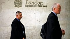 Men walk past a logo outside the London Stock Exchange in the City of London, Tuesday Oct.14, 2008.