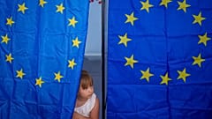 Un niño mira desde una cabina de votación durante las elecciones europeas y locales en Baleni, Rumanía.