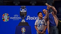 A mother with her boy takes a selfie next to the 2024 UEFA European Football Championship trophy, as it is displayed in Athens, Thursday, March 21, 2024