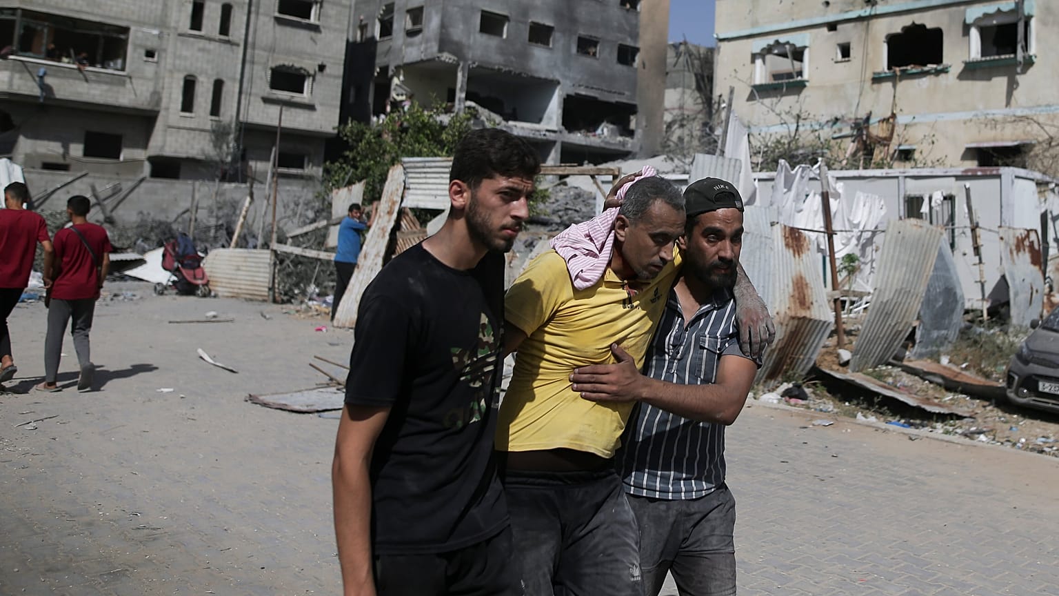 فلسطينيان يساعدان رجلاً جريحًا بعد الغارات الإسرائيلية على مخيم النصيرات للاجئين في قطاع غزة، السبت، 8 حزيران / يونيو 2024.