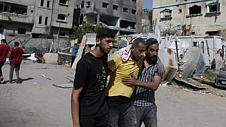 فلسطينيان يساعدان رجلاً جريحًا بعد الغارات الإسرائيلية على مخيم النصيرات للاجئين في قطاع غزة، السبت، 8 حزيران / يونيو 2024.