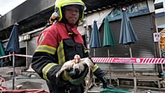 Ein thailändischer Retter trägt ein Huhn, das ein Feuer auf dem Chatuchak-Wochenendmarkt in Bangkok, Thailand, überlebt hat, 11. Juni 2024. 