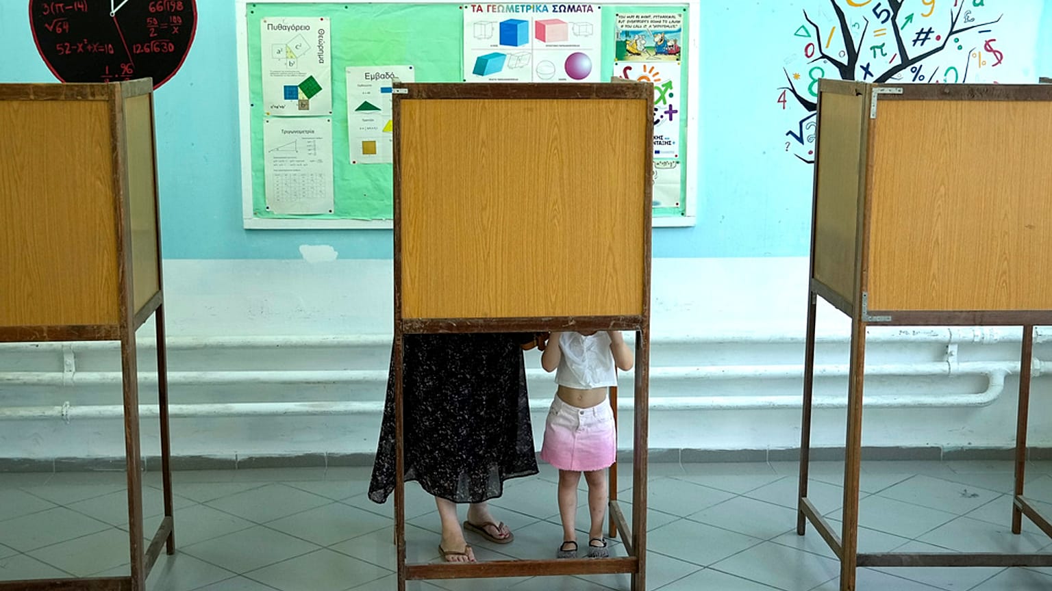 A woman with her child casts her ballot during the European and local Elections in capital Nicosia, Cyprus, Sunday, June 9, 2024. 