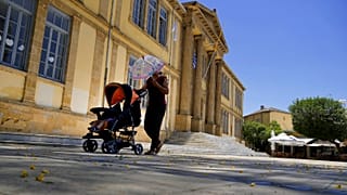  A woman protects herself from the sun with an umbrella as she push a baby in a pushchair during a hot day at Phaneromeni square in central capital Nicosia, 4 June 2024