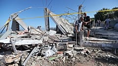 رجال لبنانيون يتفقدون منزلا مدمرا ضربته غارة جوية إسرائيلية ليلة الجمعة.
