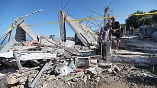 رجال لبنانيون يتفقدون منزلا مدمرا ضربته غارة جوية إسرائيلية ليلة الجمعة