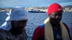 Menekültek. Háttérben a Sea Watch civil szervezet mentőhajója