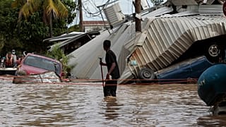 Nesta foto de arquivo de 6 de novembro de 2020, um morador caminhando por uma rua inundada olha para trás, para os danos causados pelo furacão Eta em Planeta, Honduras.