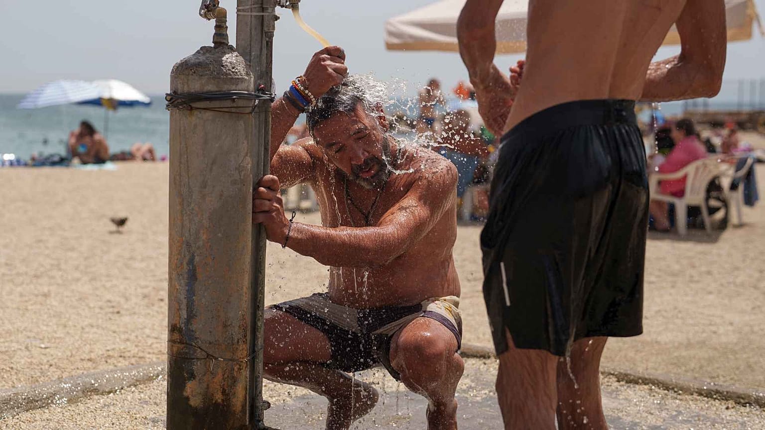 Giannis Mpekos takes a shower at a beach in Faliro seaside district of Athens, on Thursday June 13, 2024.