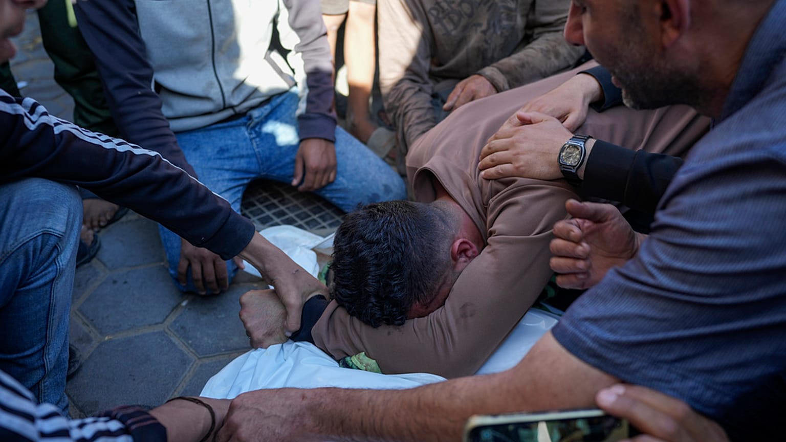 فلسطينيون يبكون خلال تشييع جثمان البالغين والأطفال الذين استشهدوا جراء القصف الإسرائيلي على قطاع غزة