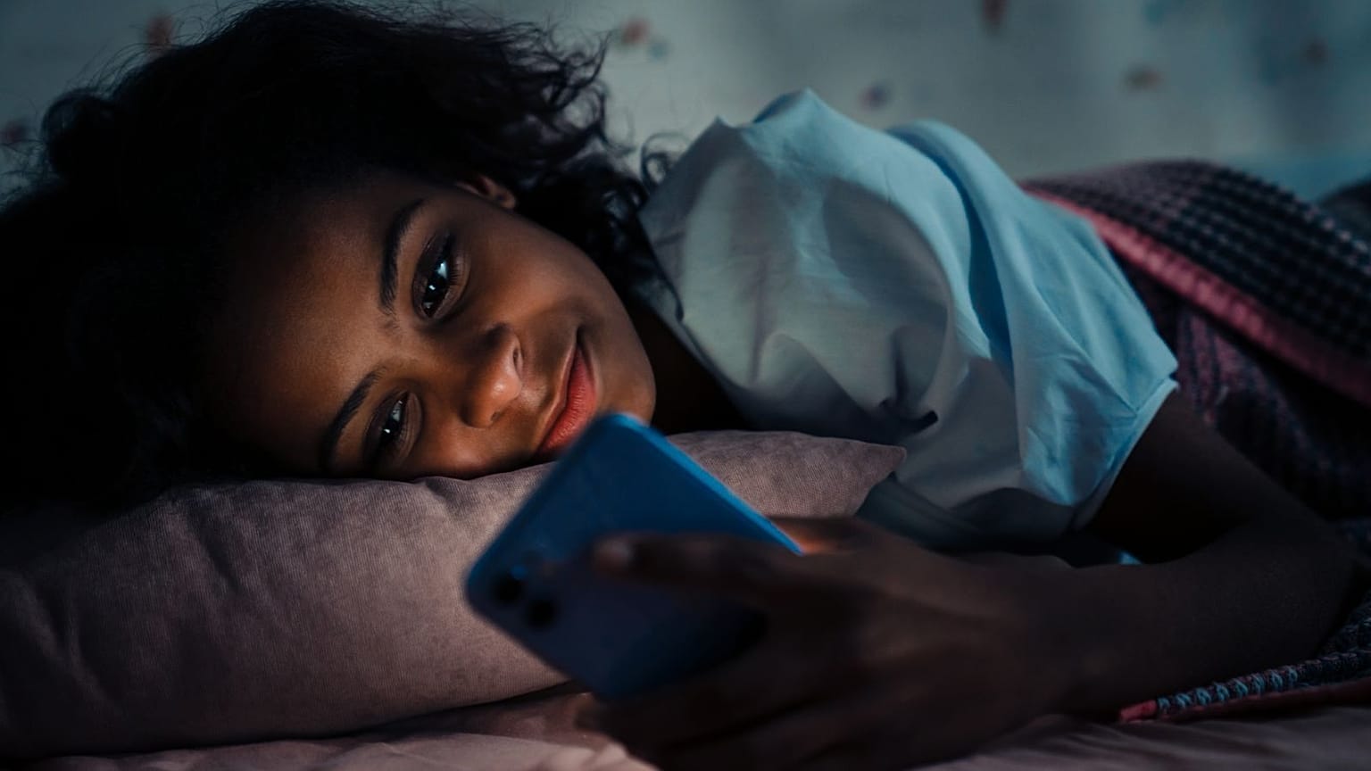 Una mujer en la cama con su teléfono.