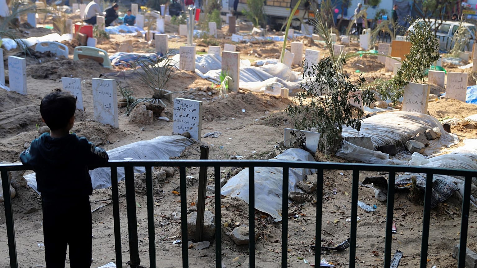  طفل فلسطيني ينظر إلى قبور قتلى القصف الإسرائيلي على قطاع غزة والمدفونين داخل أرض مستشفى الشفاء