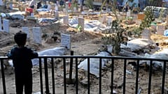  طفل فلسطيني ينظر إلى قبور قتلى القصف الإسرائيلي على قطاع غزة والمدفونين داخل أرض مستشفى الشفاء