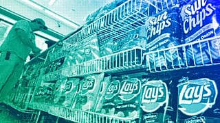 A convenience store customer make a purchase next to a shelf of snacks, in Boston, July 2005