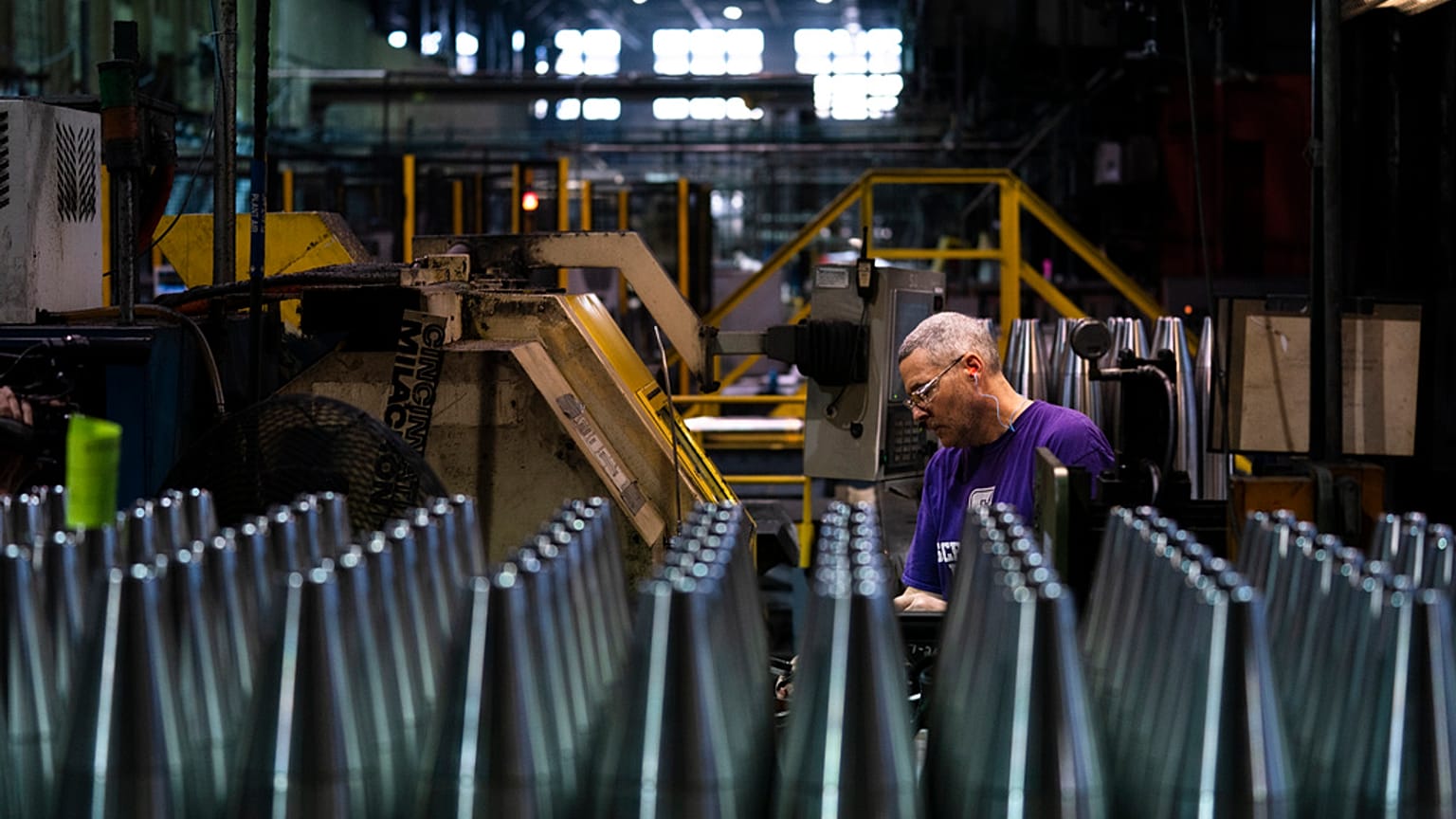 A steel worker manufactures 155 mm M795 artillery projectiles.